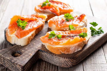 Slice of bread with smoked salmon and butter on wooden background. Grain yeast-free bread butter, parsley and fish on a wooden board.