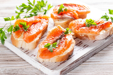 Slice of bread with smoked salmon and butter on wooden background. Grain yeast-free bread butter, parsley and fish on a wooden board.