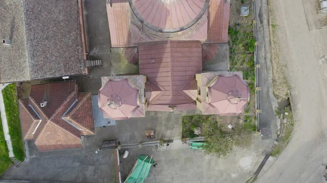 Flying over a beautiful church with a camera drone in a small village under a hill from front to the back of the church