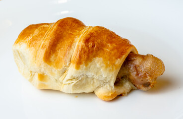 Appetizing chicken leg in puff pastry on a white plate