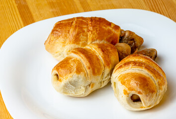 Appetizing chicken legs in puff pastry on a white plate and wooden background