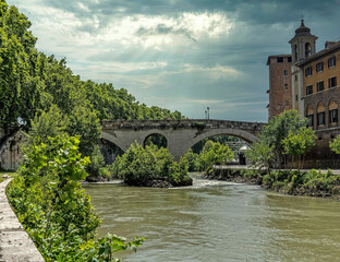 Fototapeta premium Rome Italy, Tiber island, bridge Fabricio and Caetani fortress tower view from lungotevere de Cenci under impressive sky