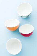 Colored bowl  orange ,yellow pink ,blue and green color flatlay, over a blue wallpaper type background, top view, flatlay