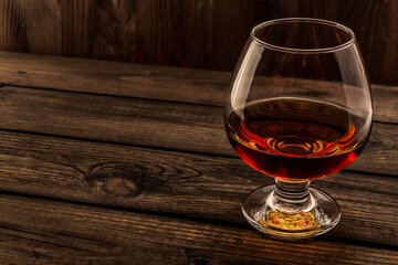 Glass of brandy and on an old wooden table. Angle view