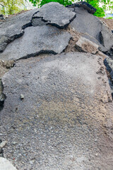 A pile of broken asphalt near a hole with broken pipes in the courtyard of an old house