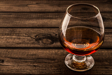 Glass of brandy and on an old wooden table. Close up view