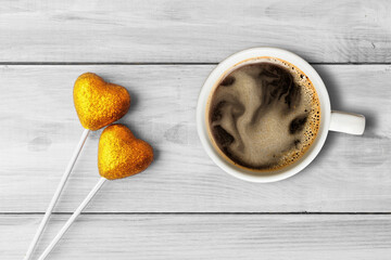 Cup of coffee and decorative yellow hearts over light wooden background