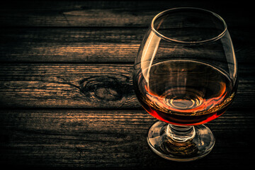 Glass of brandy and on an old wooden table. Close up view