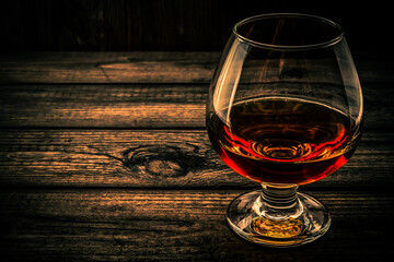 Glass of brandy and on an old wooden table. Angle view