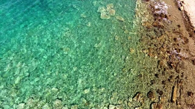 Clear and shallow sea water of the cove surrounded by stone and rocky coastline.Aerial reef untouched seashore of bright turquoise ocean.Seaboard stony rock coast seaside shore unspoiled nobody waters