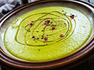 Cream green peas soup on wooden table

