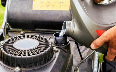 Pouring gasoline into the tank of lawn mower.