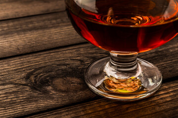 Glass of brandy on an old wooden table. Close up view