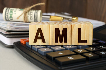 On the table are money, a calculator, a notebook and cubes with the inscription - AML