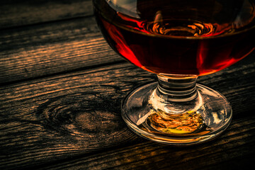 Glass of brandy on an old wooden table. Close up view