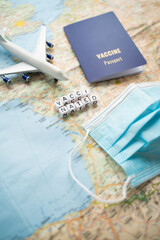 Vaccinated traveler planning booking flights and trip. Table with blue vaccine passport, map, plane...