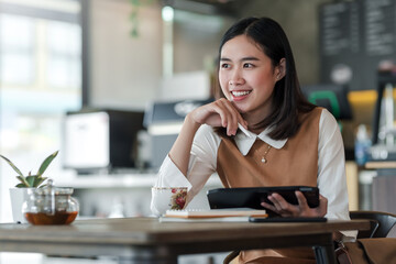Image of Asian businesswoman enjoy working life using a tablet at the café.