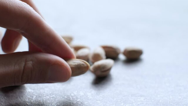 Man takes and open pistachios nut. Soft focus, close up, 4k footage. Peeling a pistachio. Nuts cracking.