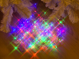 Multicolor electric garland with star shaped lights effect on the floor under the Christmas tree