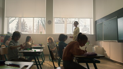 Students learning in classroom. Smart pupils writing in notebooks during lesson