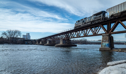 A train begins to cross a bridge over the Mississippi river near Minneapolis Minnesota under blue skies