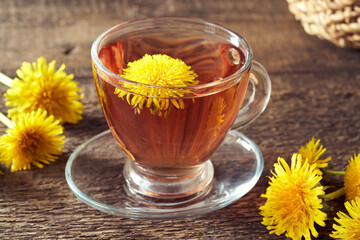 A cup of dandelion tea with fresh dandelion flowers on a table