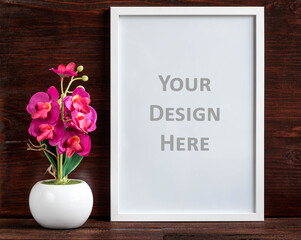 White vertical picture frame and artificial flower decoration on a dark wooden shelf. Clipping path...