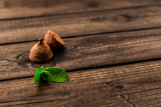 Chocolate truffles with mint sprig on an old wooden table. Close up view, shallow depth of field, focus on the mint sprig