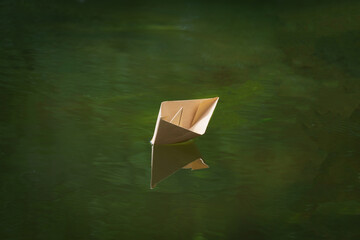 origami paper boat floats on the river. children's summer entertainment.