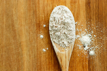 wooden spoon on wood cutting board with flour in kitchen