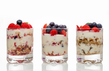 Muesli with yogurt and berries in a glass On a white background. Dessert preparation process. Fitness food. Copy space.