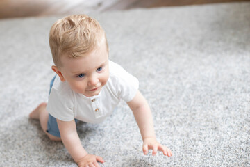 Fototapeta premium Happy baby boy crawling on carpet floor
