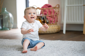 Fototapeta premium cheerful caucasian baby boy sitting on carpet 