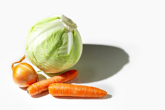 Head of cabbage, onions, carrots on a white plate. Healthy foods. Detox.
