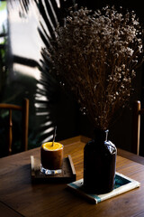 Orange cold brew coffee on a wooden table with a vase placed next to it, dark tones.