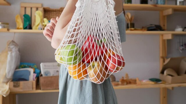 Woman in a store with a string bag of fresh food, no packaging with pasta, nuts and grains, natural soap in a store without plastic waste. Low-waste lifestyle. Sustainable ecological lifestyle
