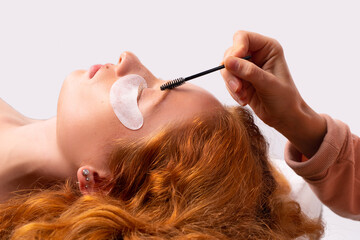 Eyebrow correction and eye makeup close-up. Master hands painting the shape of the eyebrows to a...