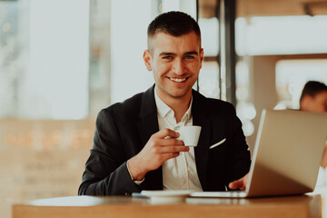 Happy business man sitting at cafeteria with laptop and smartphone