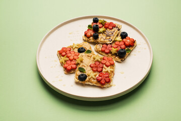 Delicious diet breakfast cereal sandwiches with peanut butter with fruits and berries on a plate, top view. Healthy food concept