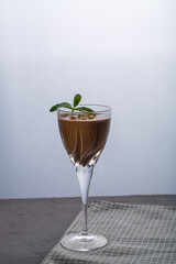 Chocolate cocktail with nuts and mint in a glass on a black background.