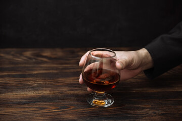 whiskey in a glass on a black background copy space. a man holds in his hand an alcoholic drink...