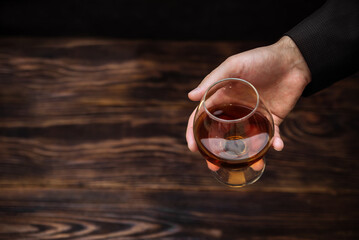 whiskey in a glass on a black background copy space. a man holds in his hand an alcoholic drink scotch, brown cognac. the concept of alcoholic drink, alcoholism