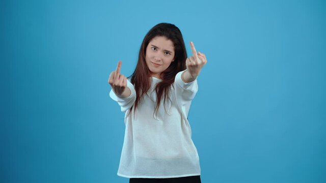 The energetic, annoyed girl looks fuck you with both hands. Asian with dark hair, dressed in a blue blouse, isolated on a dark blue background in the studio. The lifestyle concept of sincere emotions