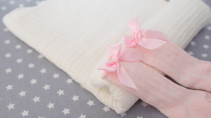 New born baby girl's pink socks with bow on a white blanket. Childhood and present concept 