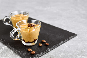 Traditional Italian dessert coffee cream in a glass cup on gray stone background. National cuisine recipe. Delicious summer refreshing mousse.