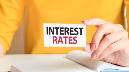 text interest rates written on a white paper card in woman hand, concept