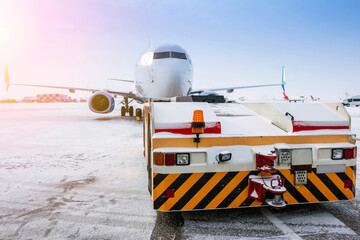 Tow tractor pushes the passenger aircraft at the cold winter airport apron