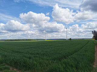 Windräder in grüner Landschaft mit bewölktem Himmel