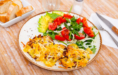 Traditional Russian meat dish Veal Orloff served with baked potato slices and salad of fresh vegetables and greens .