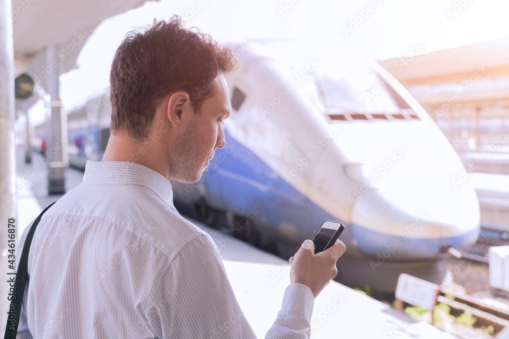 Wall mural person using app on smartphone during business travel with train in background, mobile internet tech